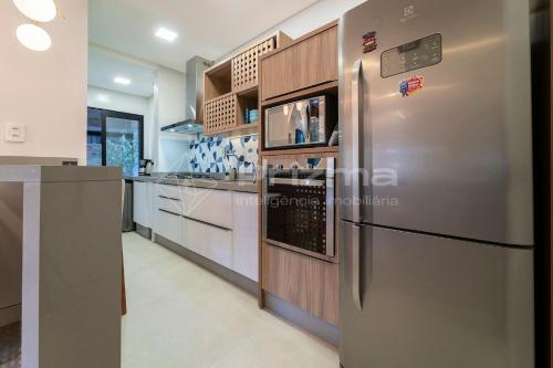 Il comprend une grande cuisine équipée d'un réfrigérateur en acier inoxydable. dans l'établissement 304 Bl 02 - WaldGarten Bombinhas - 50m do Mar e Frente Avenida - Condomínio de Alto Padrão - Piscina - Academia - Salão de jogos, à Bombinhas