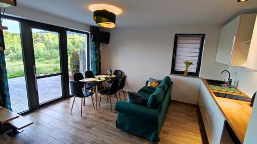 ein Wohnzimmer mit einem grünen Sofa, einem Tisch und Stühlen in der Unterkunft Blu Raj - domy w Sudetach in Głuszyca