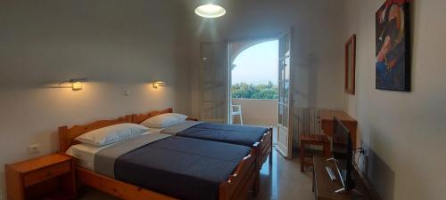 a bedroom with a bed and a large window at BOSCO VERDE Corfu Apartments in Gouvia
