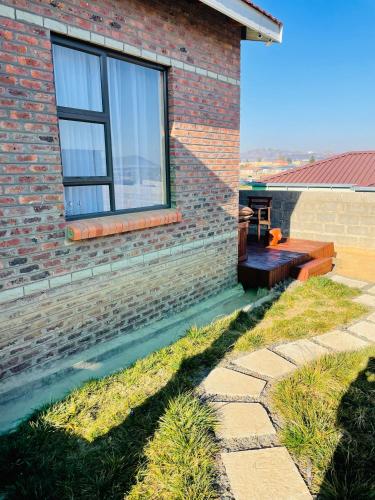 a brick house with a bench and a window at Moh Ville Guest House in Maseru