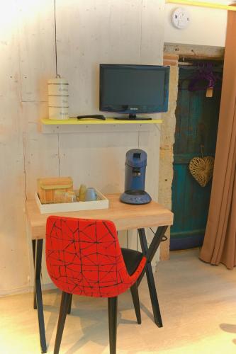 une chaise rouge assise à une table avec une télévision dans l'établissement LACOSTE, à Sainte-Colombe-en-Bruilhois