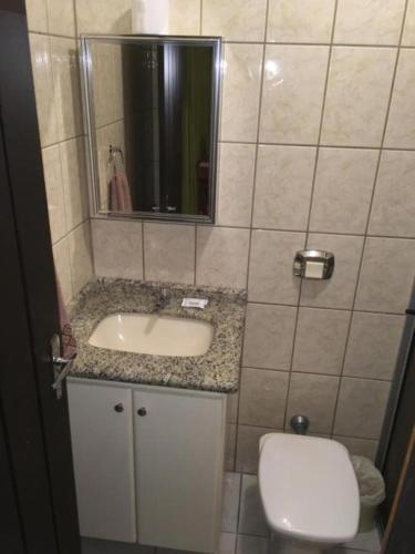 a bathroom with a sink and a toilet and a mirror at VOA Samuka Hotel in Florianópolis