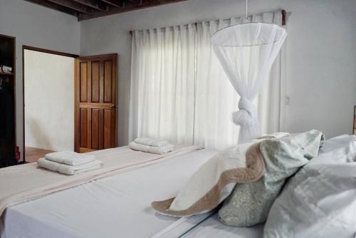 a white bedroom with a bed and a window at Casa Moes in Cahuita