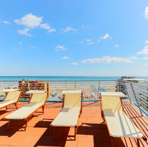 里米尼的住宿－金色翅膀酒店，俯瞰大海的阳台的一排椅子