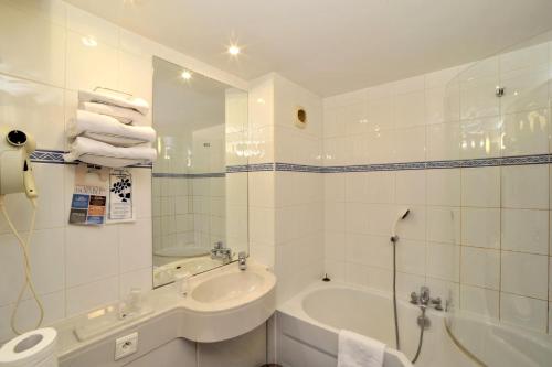 La salle de bains blanche est pourvue d'une baignoire, d'un lavabo et d'une baignoire. dans l'établissement Kyriad Annecy Cran-Gevrier, à Annecy