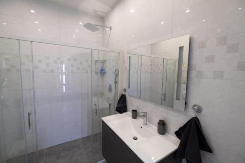 a white bathroom with a sink and a shower at Villa Kula in Bihać