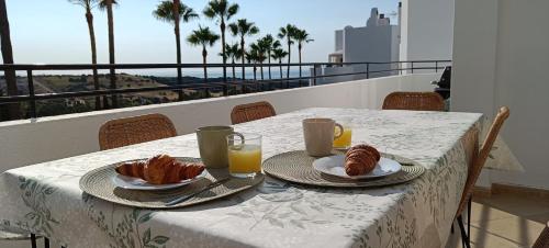 stół z dwoma talerzami rogalików i soku pomarańczowego w obiekcie Estepona Golf Apartment w mieście Estepona
