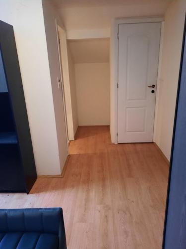 an empty room with a blue couch and a white door at Ferienwohnung Süß in Kovanluk