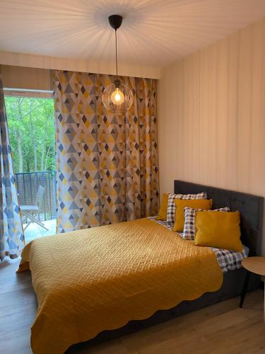 - une chambre avec un lit et une couette jaune dans l'établissement Apartamenty Poproszę Nad Morze, à Jastrzębia Góra