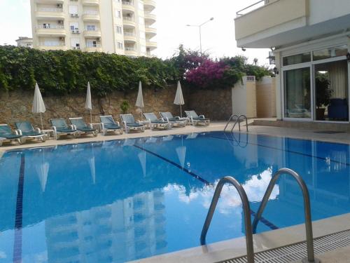 una gran piscina con tumbonas y un edificio en Orange Grove Apart Hotel, en Alanya