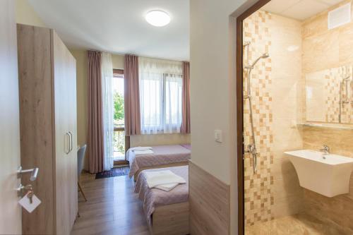 une salle de bain avec deux lits et un lavabo et une douche dans l'établissement Къща за гости Перуника, à Sapareva Banya