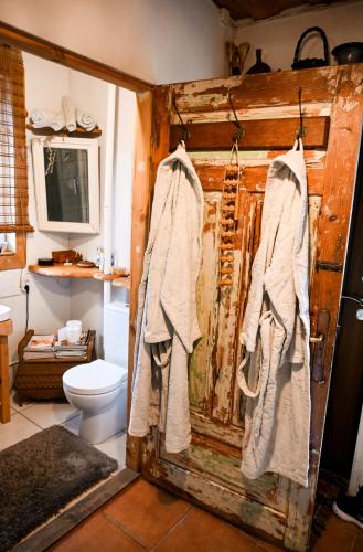 a bathroom with a toilet and towels hanging on a wall at Idilliska Latgaliešu lauku māja ar melno pirti in Aglona