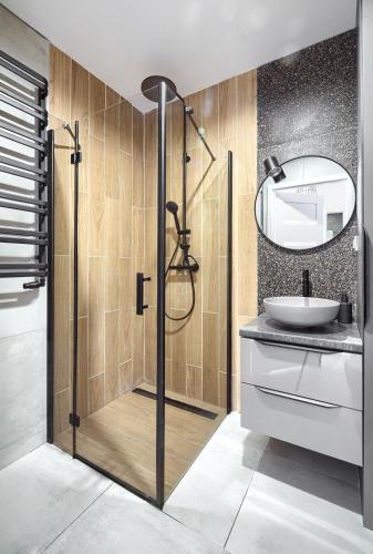 a bathroom with a shower with a sink and a mirror at Navy Blue Dream - SPA - Basen - Parking in Dziwnów