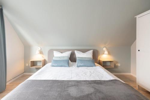 - une chambre avec un grand lit et 2 oreillers bleus dans l'établissement Tante Tine, à Husum