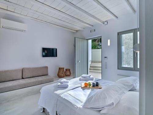 een witte slaapkamer met een bed en een bank bij Perivoli Luxury Homes, Paros in Dhragoulás
