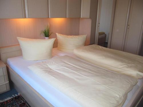 a bed with white sheets and pillows on it at Lornsenhof App 6 in Westerland