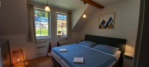 niewielka sypialnia z niebieskim łóżkiem i 2 ręcznikami w obiekcie Horní Mísečky Apartmán E25 u sjezdovky, max 6 osob w mieście Horni Misecky