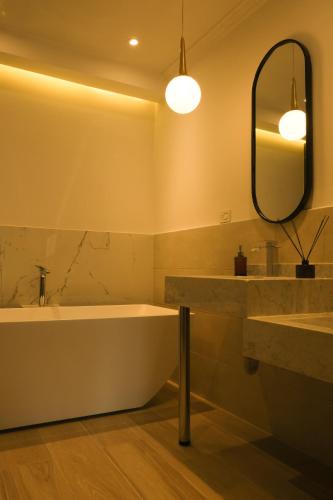 a bathroom with a tub and a sink and a mirror at El Zócalo Hotel Boutique in Filandia