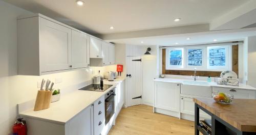 Humbug Cottage في ماتش وينلوك: مطبخ أبيض مع دواليب بيضاء ومغسلة