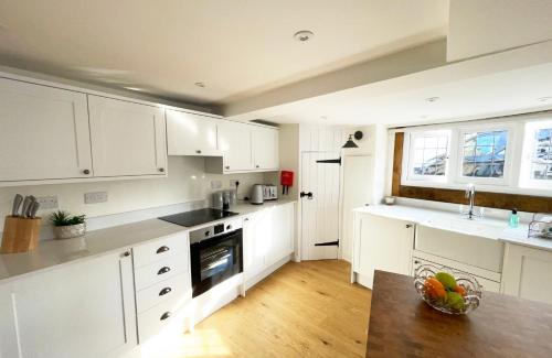 a kitchen with white cabinets and a bowl of fruit on the counter at Humbug Cottage in Much Wenlock