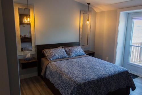 een slaapkamer met een bed met een blauw dekbed en een raam bij Dildo Boathouse Inn in Dildo