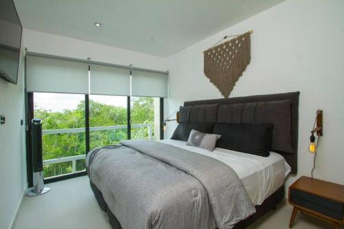 ein Schlafzimmer mit einem großen Bett und einem großen Fenster in der Unterkunft Beautiful Penthouse with Private Pool Amazing Views in Tulum