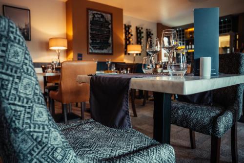 een eetkamer met een tafel en stoelen met wijnglazen bij The Bull Inn in Woolpit