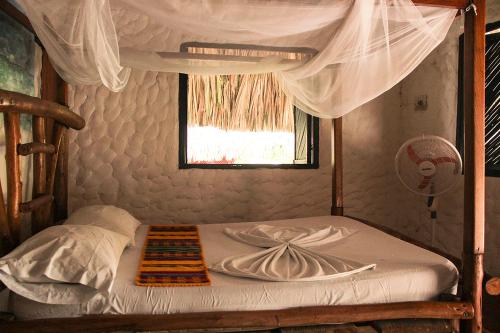 a bed in a room with a canopy at Praba Hostel in Palomino