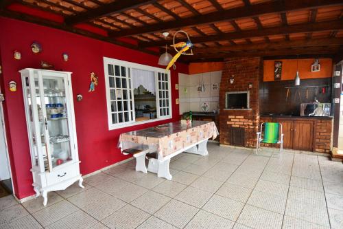 a kitchen with a red wall with a table in it at Beto Pousada in Penha