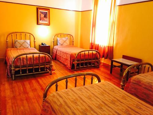 a hotel room with three beds and a table at Hotel Isabel in Mexico City