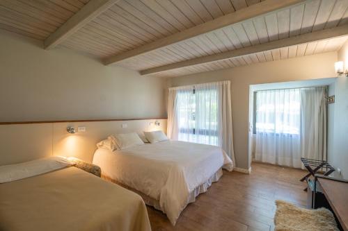 a bedroom with two beds and a large window at Atelier Hotel Charme & Spa in Villa General Belgrano