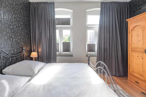 1 dormitorio con cama blanca y cortinas grises en Quartier 41, en Husum