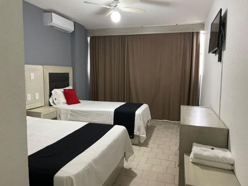Cette chambre comprend deux lits et un ventilateur de plafond. dans l'établissement Hotel Italia, à Aguascalientes