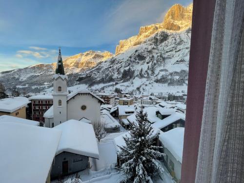 a village covered in snow with a church and a mountain at Hotel Restaurant Escher in Leukerbad