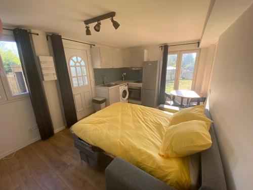 a bedroom with a yellow bed and a kitchen at Une pause en Ile de France - 450 M RER E in Villiers-sur-Marne