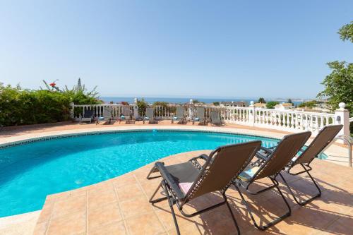 a swimming pool with chairs and the ocean in the background at Villa del Sol - Entre Tu y Yo in Benalmádena