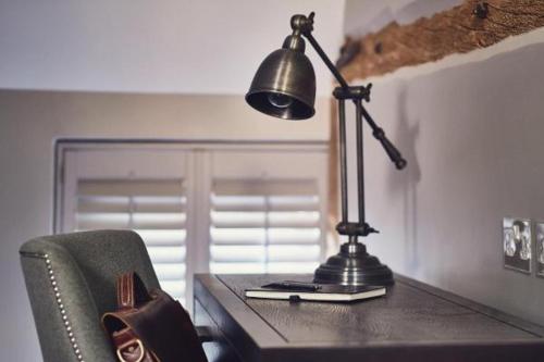 a desk with a lamp on a table with a chair at Marquis Suffolk in Ipswich