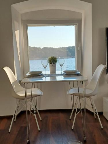 a dining room table with two wine glasses and a window at Niko 1 in Mali Lošinj