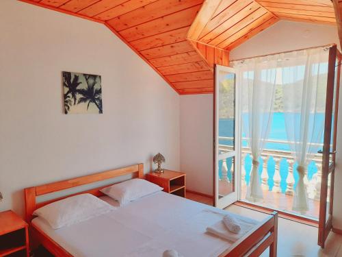 ein Schlafzimmer mit einem Bett und einem großen Fenster in der Unterkunft Apartments Sponga in Polače