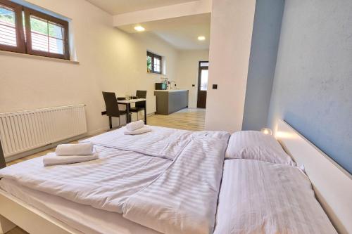 a large white bed in a room with a table at AUžlak hiša, apartments. in Luče