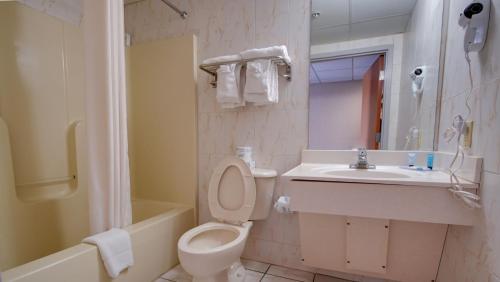 a bathroom with a toilet and a sink and a tub at Ocean 1 Hotel & Suites Ocean City in Ocean City