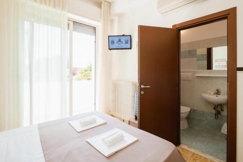 a bedroom with a bed and a toilet and a window at Hotel Villa del Mare in Senigallia