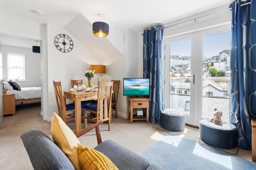 a living room with a table and a dining room at A modern and cosy apartment just yards from Brixham’s bustling harbourside in Brixham
