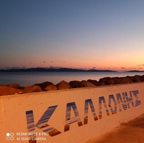 een bord op het strand met de zonsondergang op de achtergrond bij Angel's Houses in Skala Kallonis