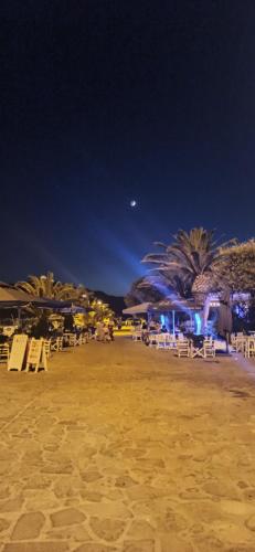 a sandy beach at night with chairs and palm trees at Angel's Houses in Skala Kallonis