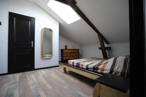 1 dormitorio con cama y espejo en la pared en Appartement neuf climatisé, en Aramits