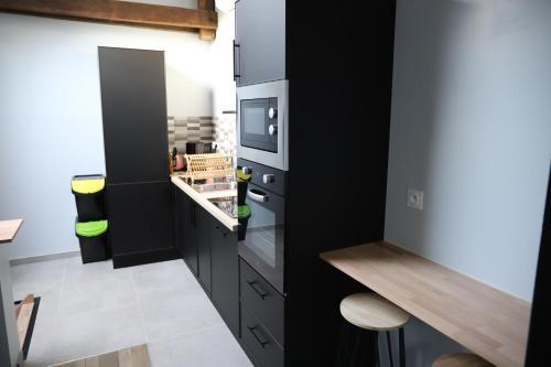 a kitchen with black cabinets and a black refrigerator at Appartement neuf climatisé in Aramits