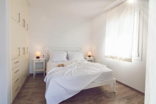 a white bedroom with a white bed and a window at Vassiliki Residence Skyros Island in Skiros