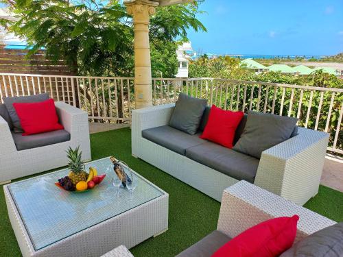 eine Terrasse mit Sofas und einem Tisch mit einer Obstschale in der Unterkunft Spacious Villa with Ocean and Mountain view-4 beds in Cul de Sac