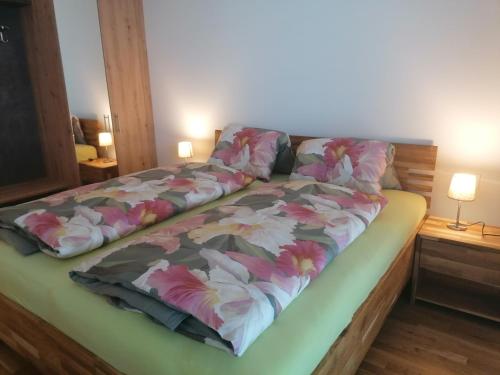 a bed with a floral comforter on top of it at Apartment Augenweide in Annenheim